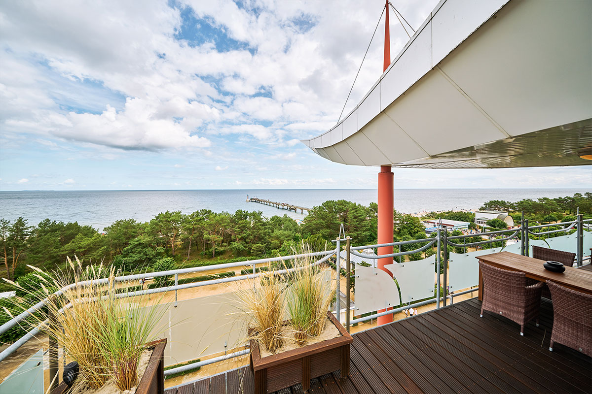 Große Dachterrasse im Penthouse des Strandhotel Prinz von Preussen mit Meerblick, Glasgeländer und Sitzmöbeln.