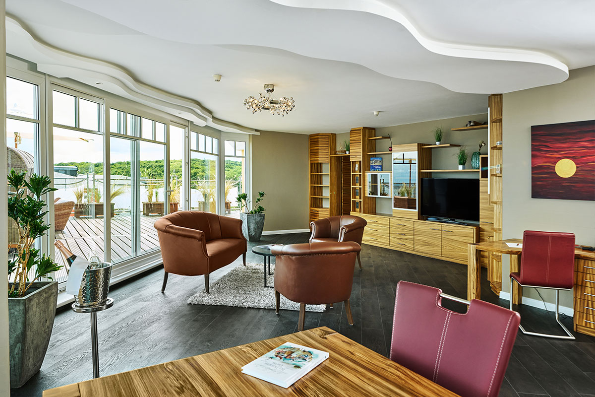 Offener Wohnbereich im Strandhotel Prinz von Preussen mit Fernsehecke, Glastüren zur Terrasse und stilvoller Einrichtung.