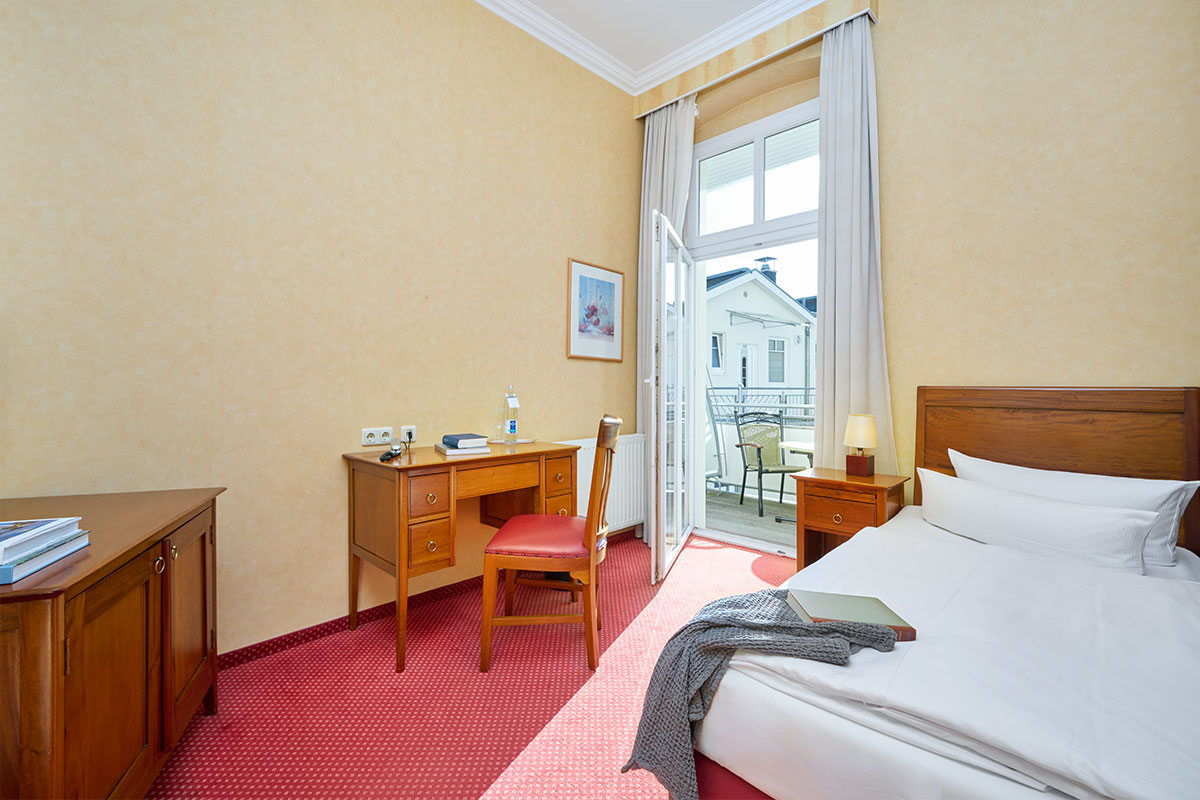 Helles Einzelzimmer in der Strandvilla Viktoria von Schöner Inseln auf Usedom mit Zugang zum Balkon und klassischer Möblierung.
