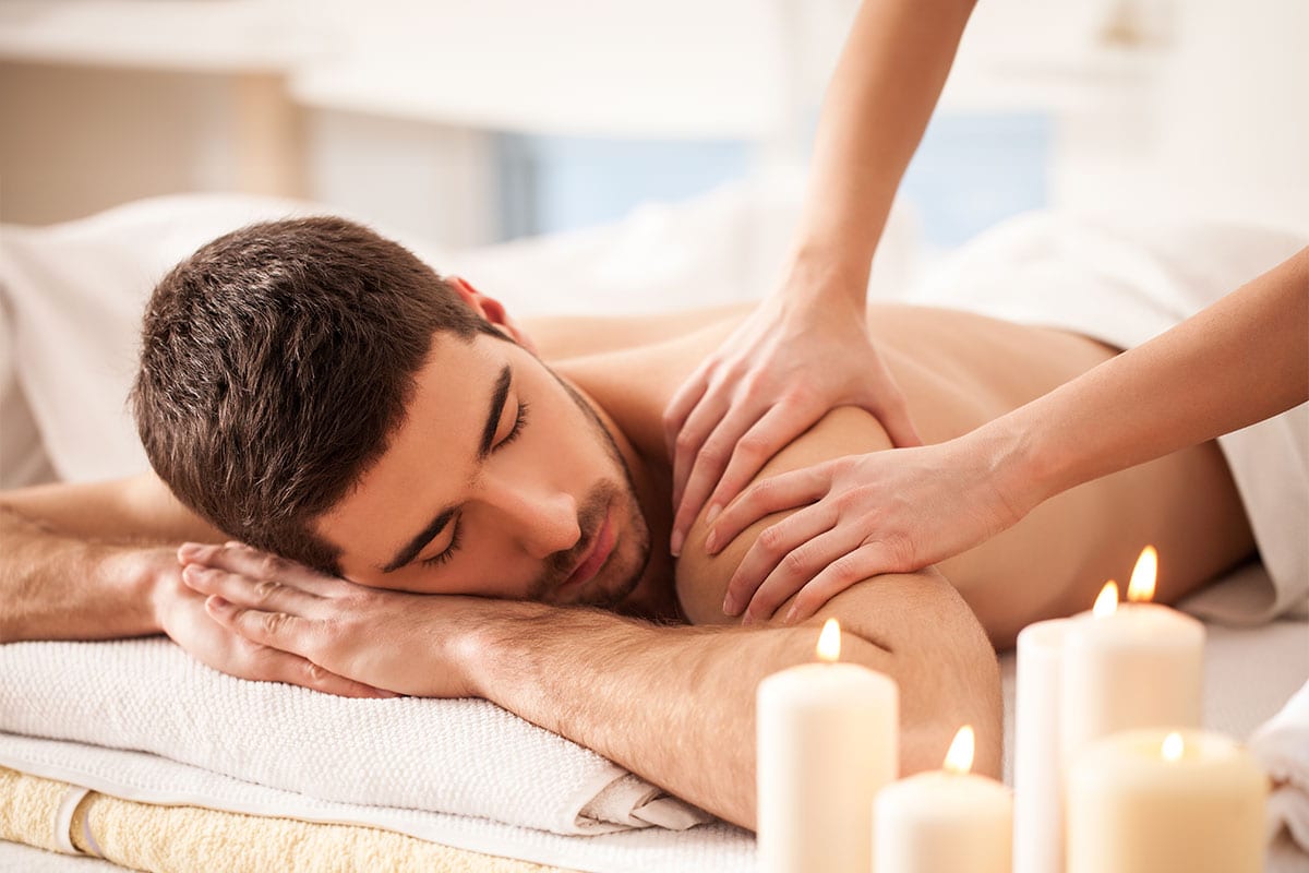 Mann liegt entspannt auf Massageliege mit Kerzen-Deko im Preussen-Vital-Spa von Schoener Inseln auf Usedom.