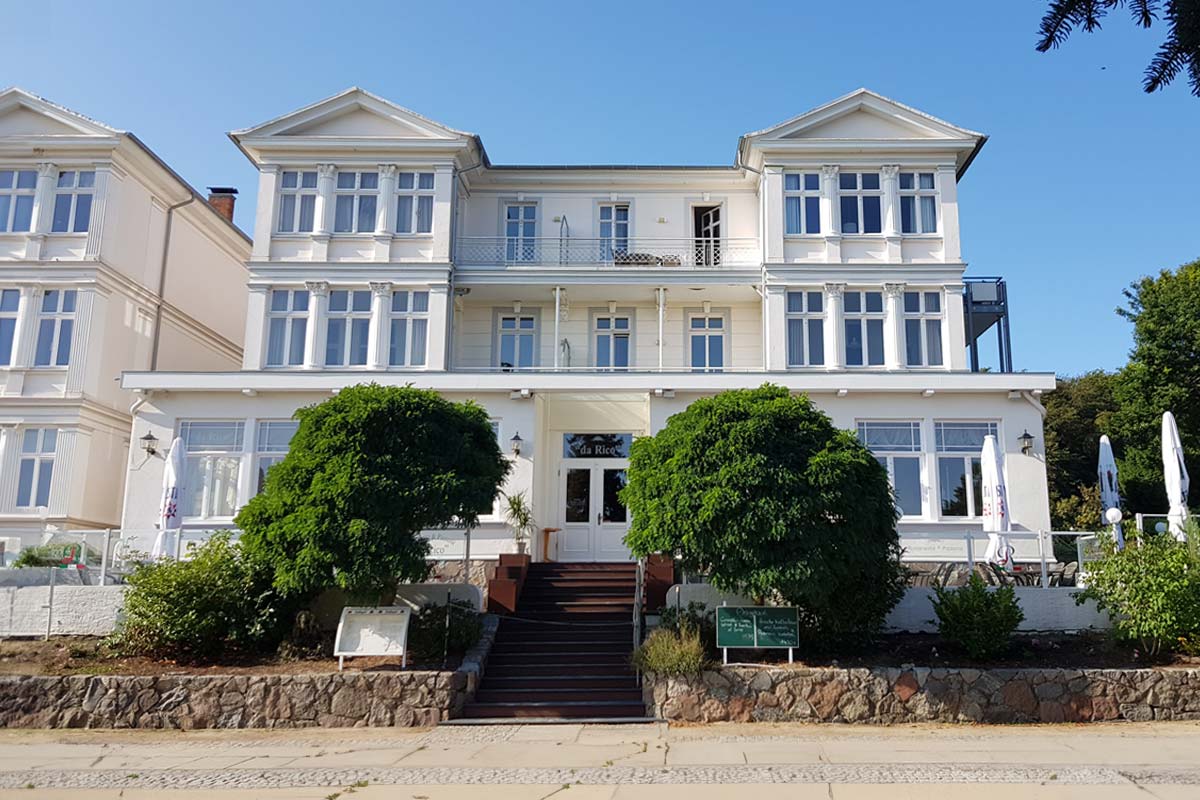 Historische Fassade des Zinnowitzer Hofs von Schoener Inseln auf Usedom mit weißen Erkern und Terrassen im Eingangsbereich.