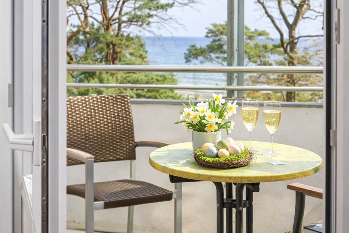 Frühlingshafte Balkon-Szene mit Meerblick auf Usedom: gedeckter Tisch mit Blumen und Sekt