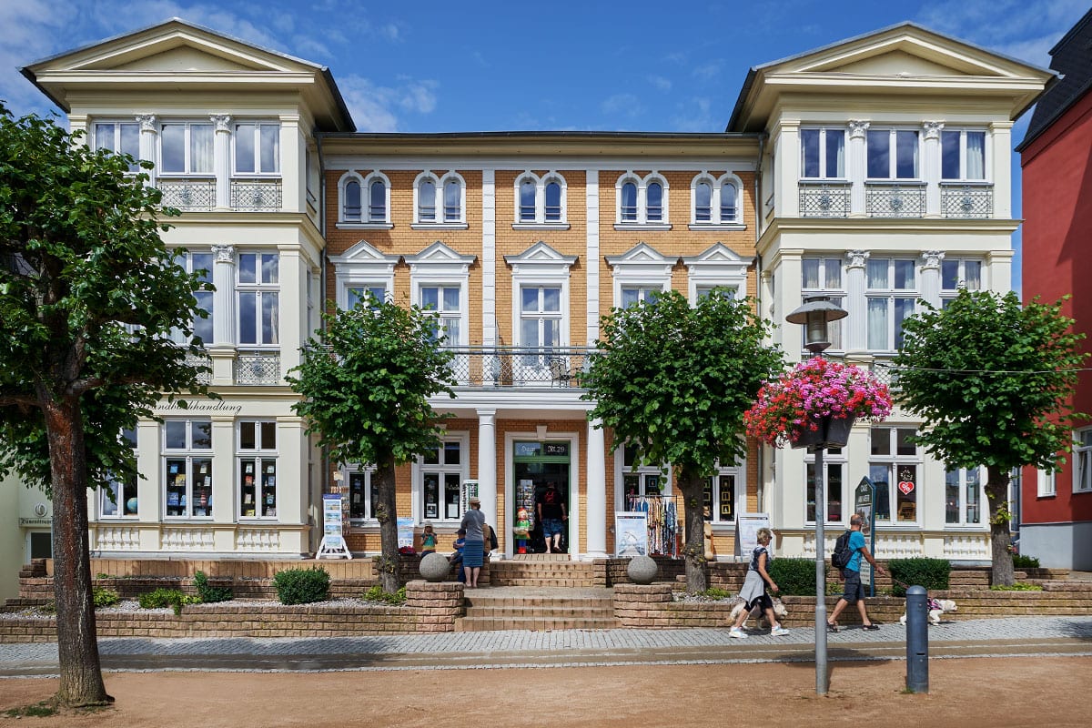 Das historische Strandhotel Viktoria auf Usedom mit Bäderarchitektur im Ortskern von Zinnowitz, davor blühende Bäume.
