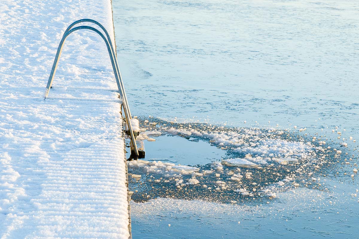 Verschneiter Steg mit Leiter und aufgebrochenem Eisloch für das Eisbaden in der Ostsee in Zinnowitz.