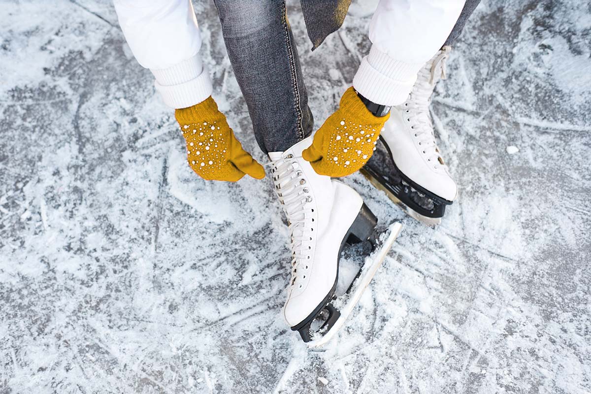 Person schnürt Eislaufschuhe auf der Eisfläche von Zinnowitz on Ice, umgeben von winterlichem Ambiente.